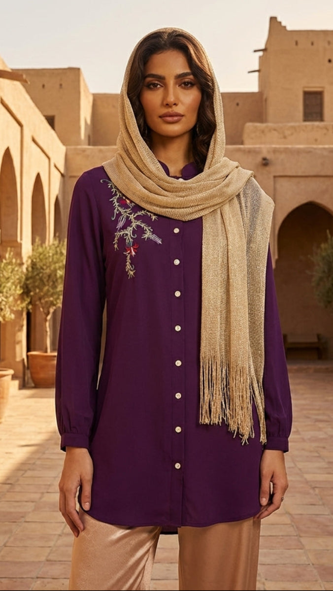Woman in a purple outfit with a beige scarf standing in a sunlit courtyard with arches and plants.