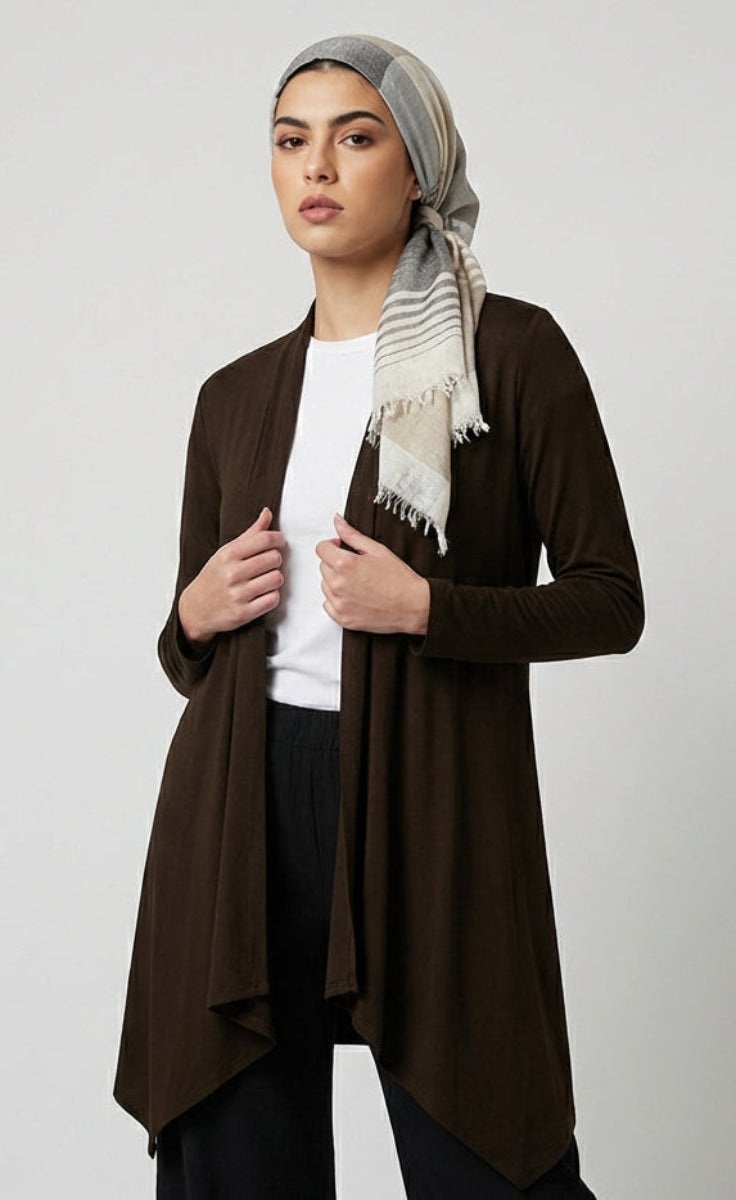 Woman wearing a brown cardigan over a white shirt with a patterned scarf on a light gray background