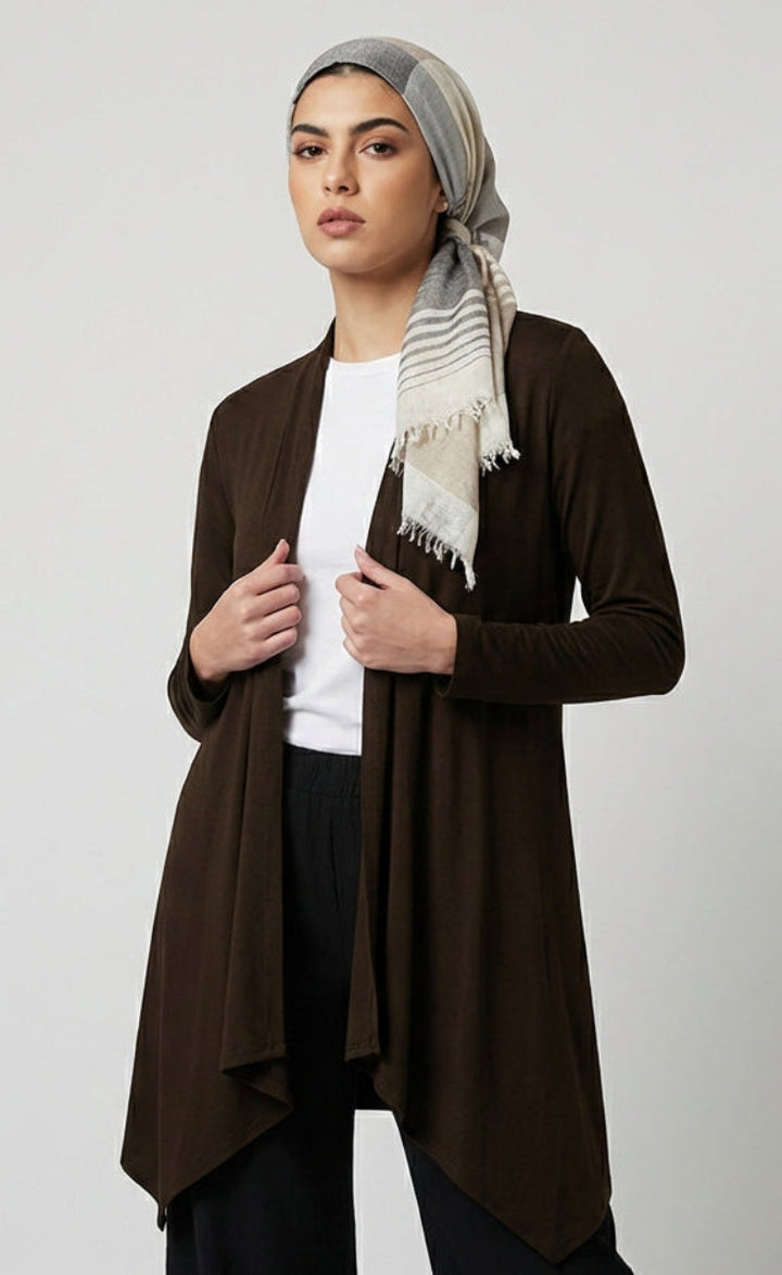 Woman wearing a brown cardigan over a white shirt with a patterned scarf on a light gray background