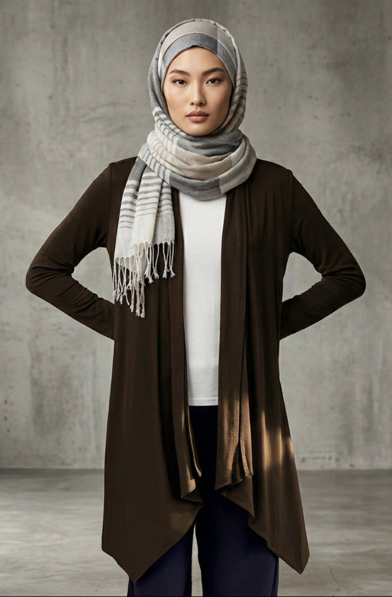 Woman wearing a brown cardigan, white shirt, and patterned scarf against a gray background
