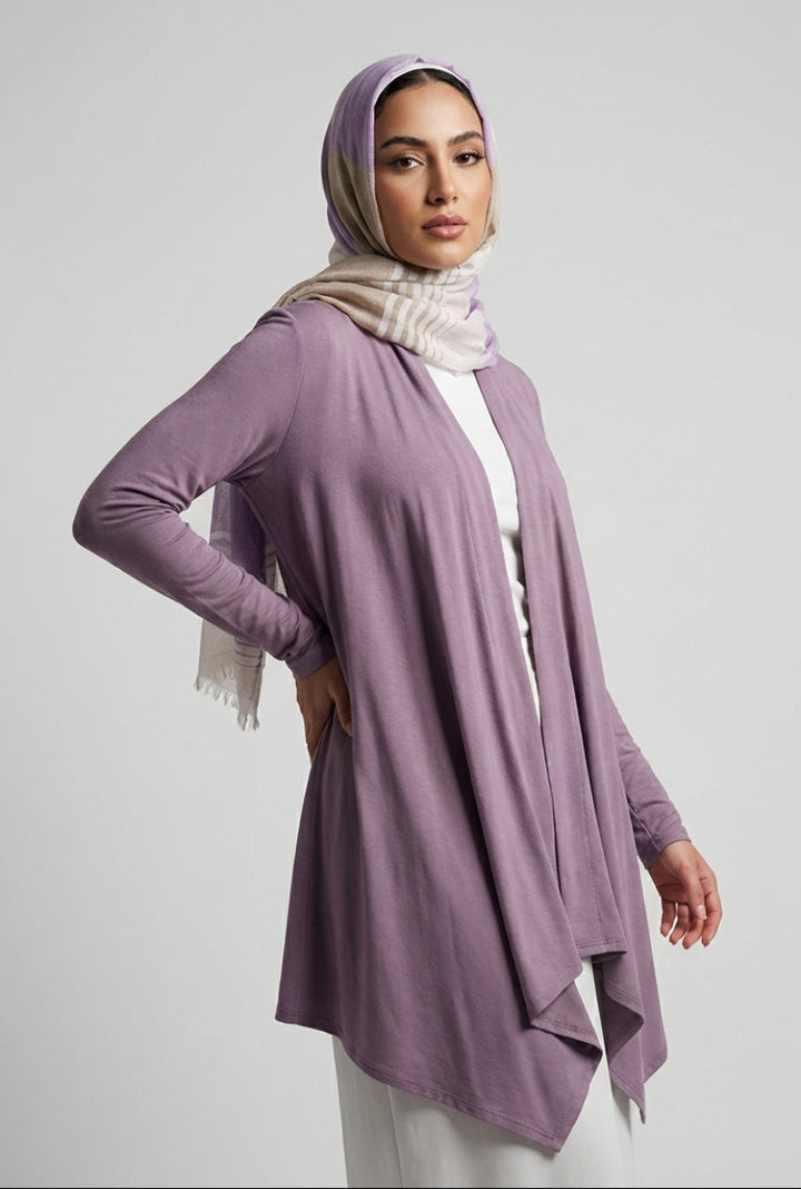 Woman wearing a long purple cardigan over a white top with a hijab on a light gray background