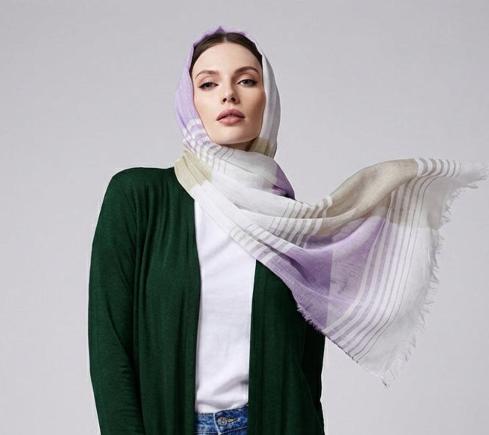 Woman wearing a green cardigan, white shirt, blue jeans, and a colorful scarf on a plain background