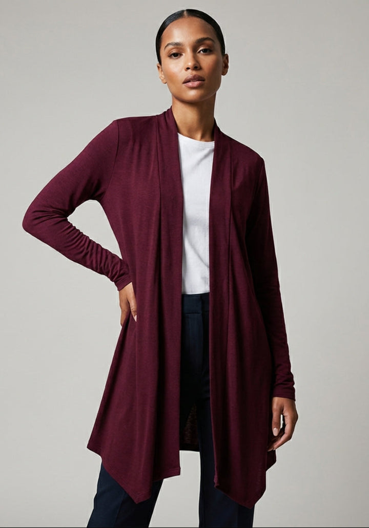 Woman wearing a burgundy cardigan over a white shirt and dark pants on a plain background