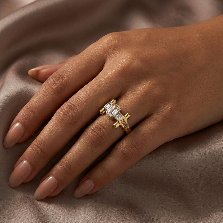 Gold ring with a diamond on a hand against a brown fabric background