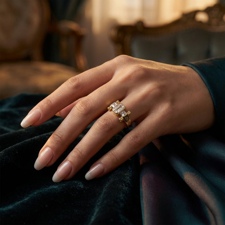 Hand wearing a gold ring with a diamond on a dark fabric background