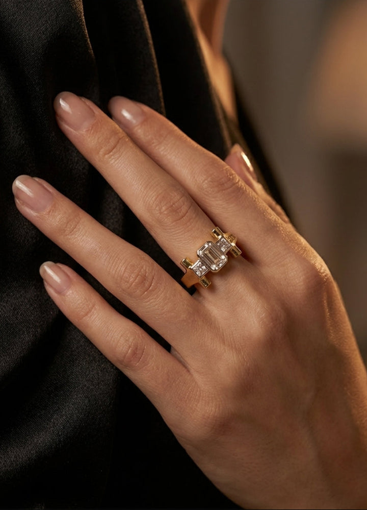 Close-up of a hand wearing a gold ring with a diamond on a blurred background