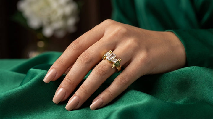 Hand wearing a gold ring with a diamond on a green fabric background