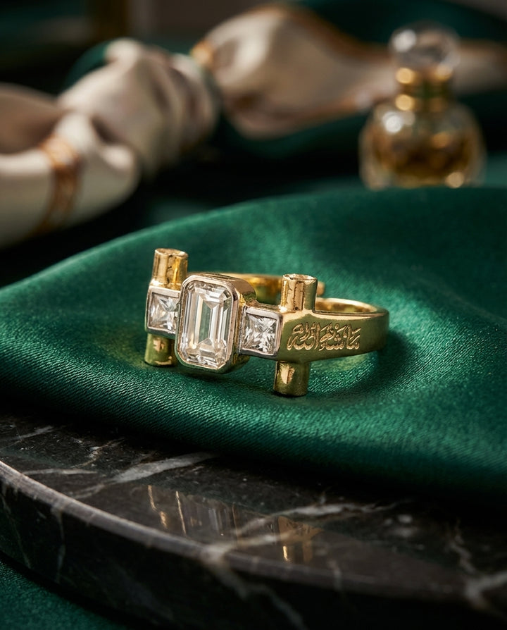Gold ring with emerald-cut center stone and diamond accents on a green fabric background