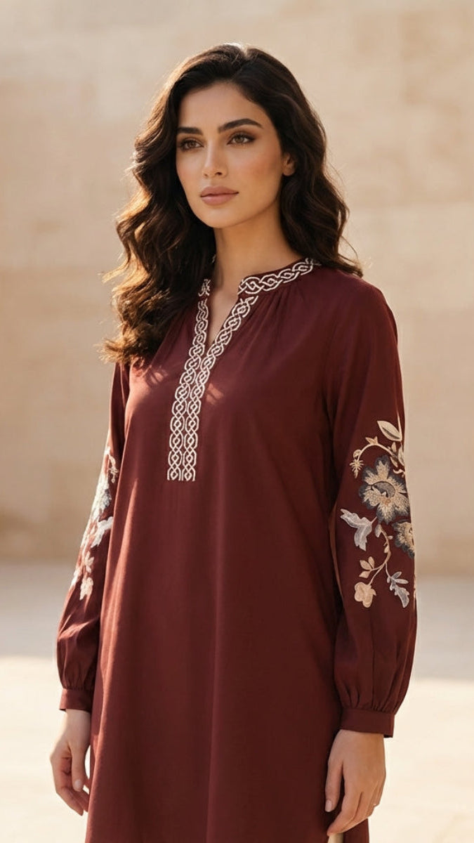 Woman wearing a burgundy dress with floral embroidery in an outdoor setting