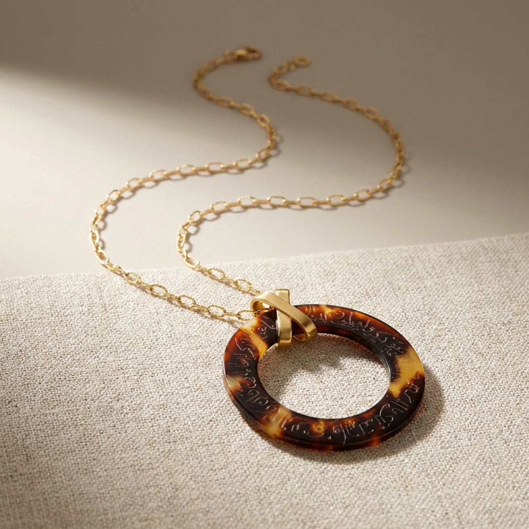 Necklace with arabic calligraphy engraved  tortoiseshell pendant on a beige background