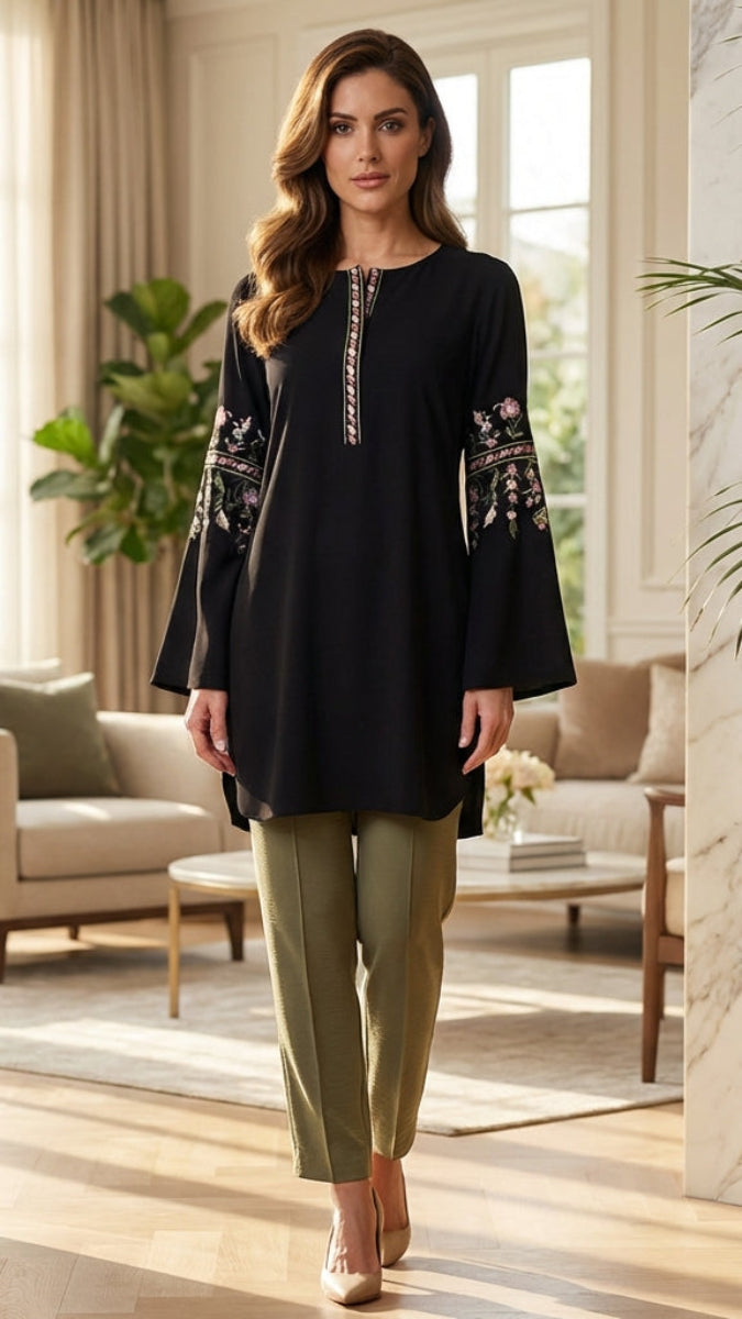Woman in a stylish outfit standing in a modern living room with decor elements.