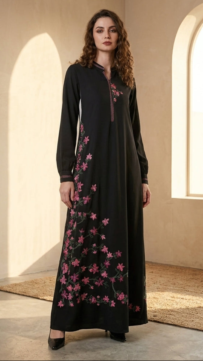 Woman wearing a black dress with pink floral embroidery in a sunlit room.