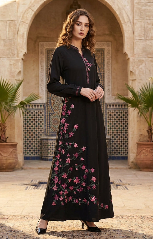 Woman wearing a black dress with pink floral embroidery in an outdoor setting.
