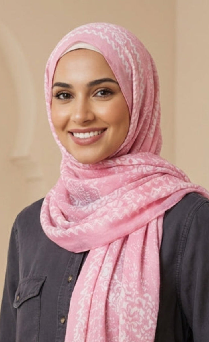 Woman wearing a pink hijab and dark shirt against a beige background