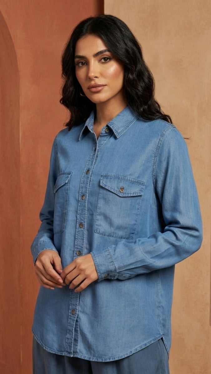 Woman wearing a blue denim shirt in a warm-toned architectural setting