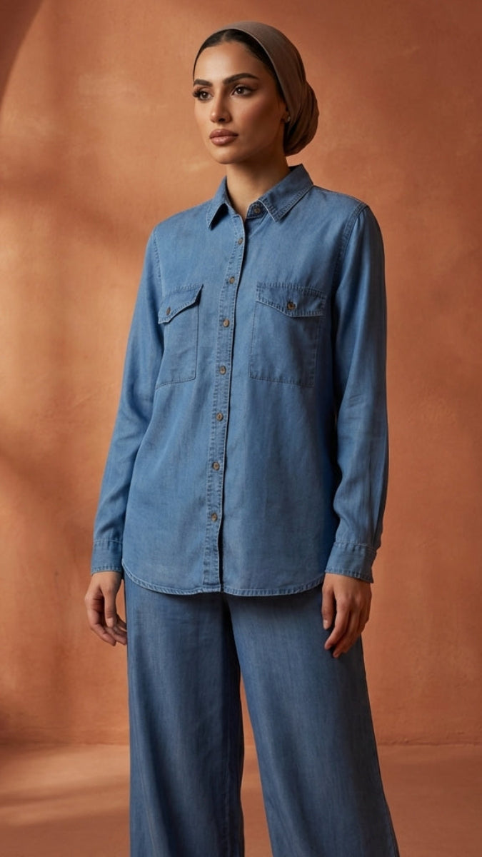 Woman wearing a blue denim outfit against a warm-toned wall.