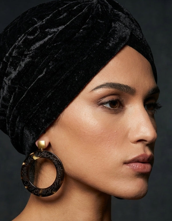 Woman wearing a black velvet turban against a dark background