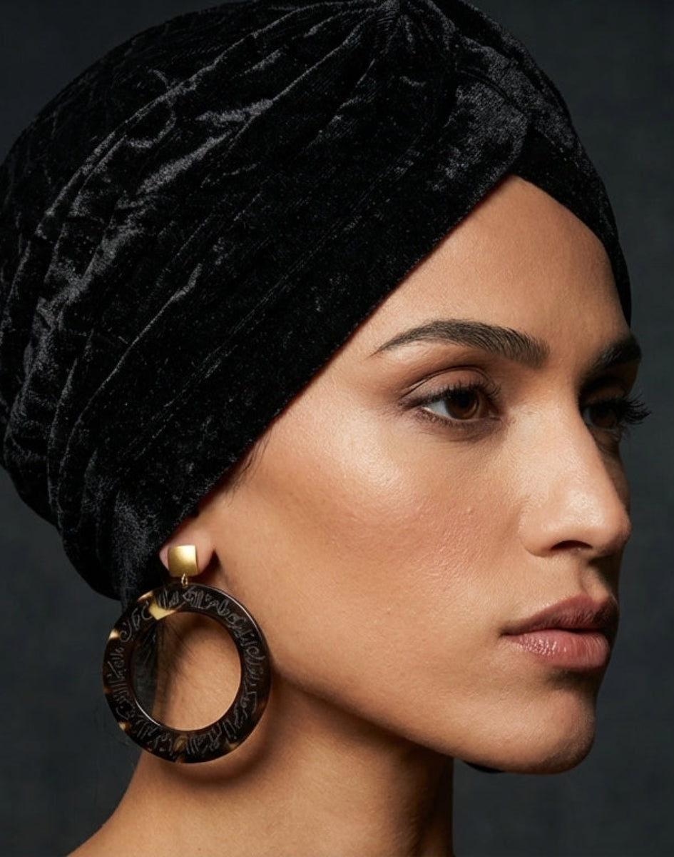 Woman wearing a black velvet turban against a dark background