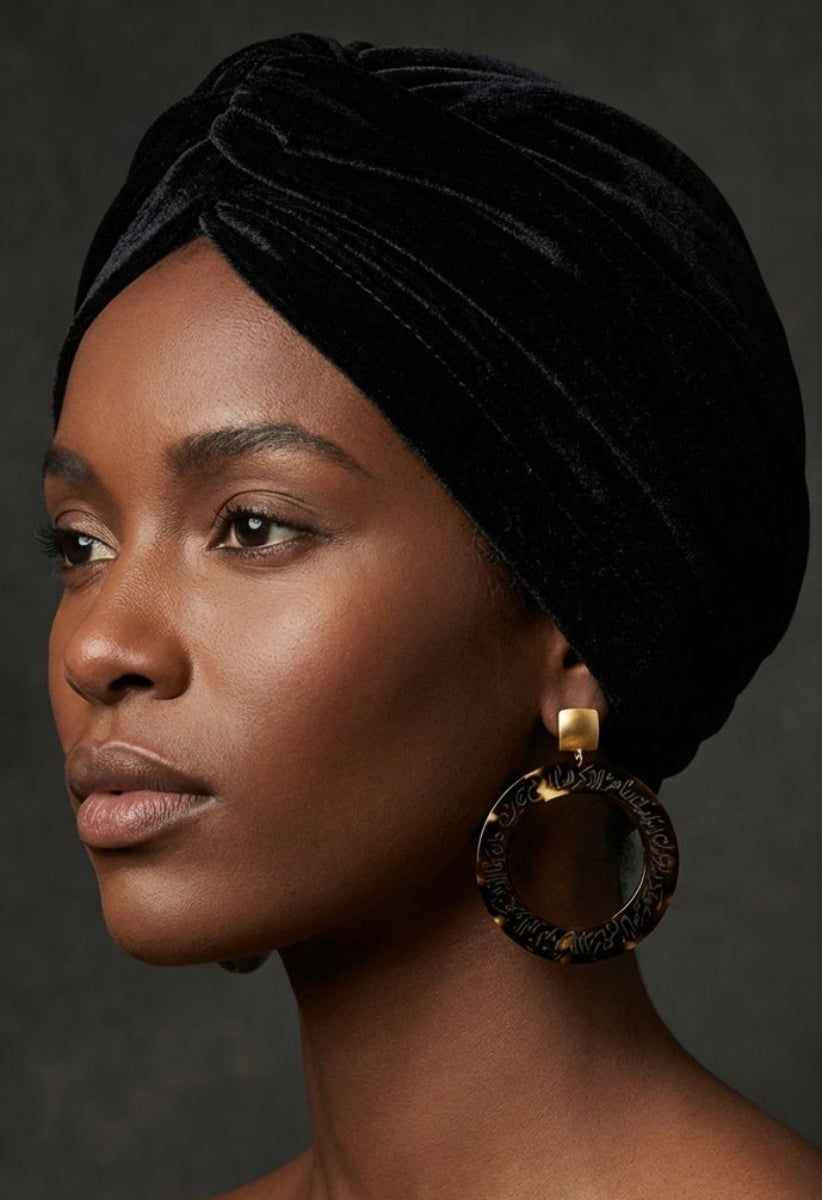 Woman wearing a black velvet turban against a dark background