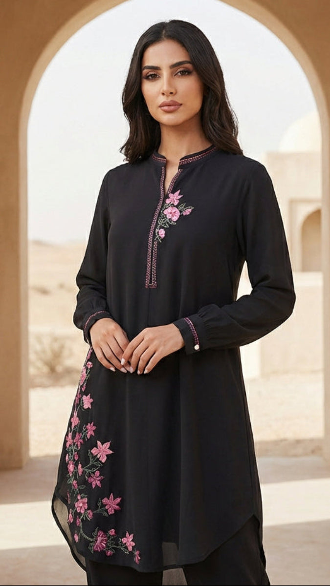 Woman wearing a black embroidered dress standing in an archway with a desert background