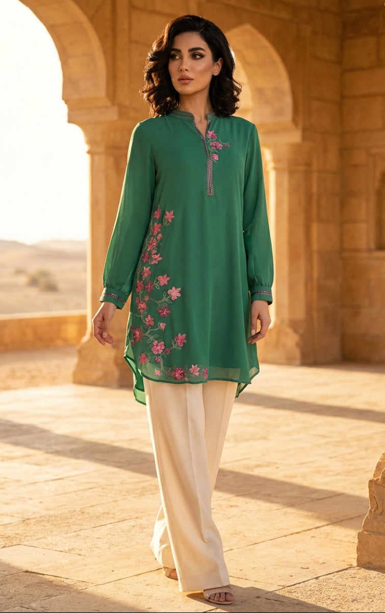 Woman in a green embroidered outfit standing in an architectural setting with arches and columns.