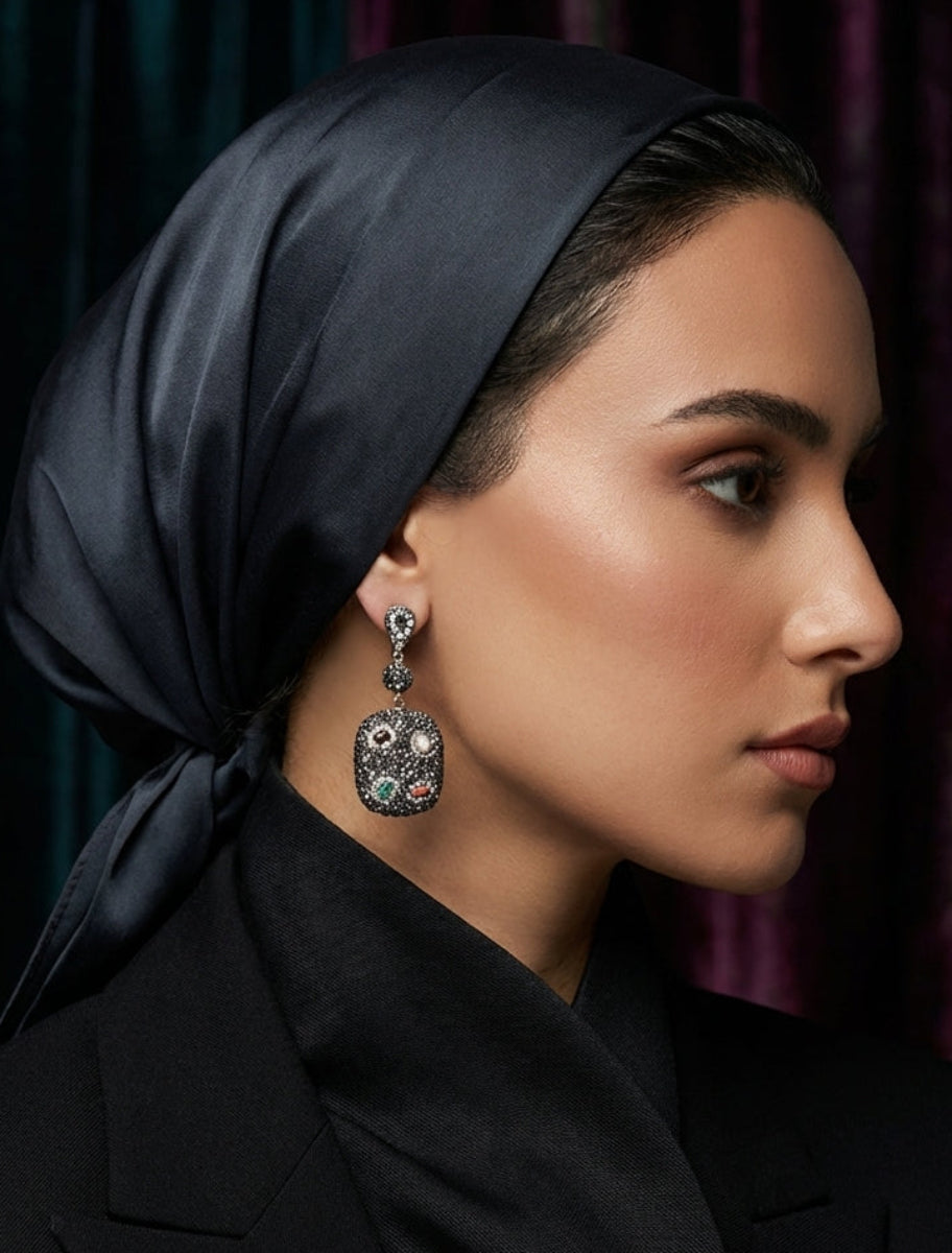 Woman wearing a black headscarf and black coat with a dark background