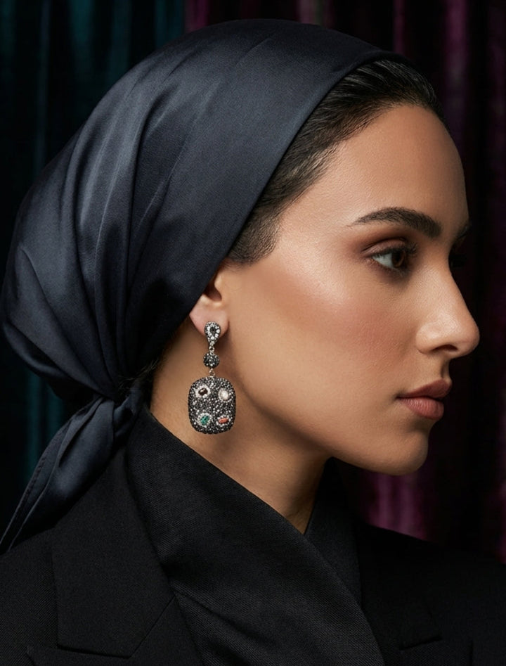 Woman wearing a black headscarf and black coat with a dark background