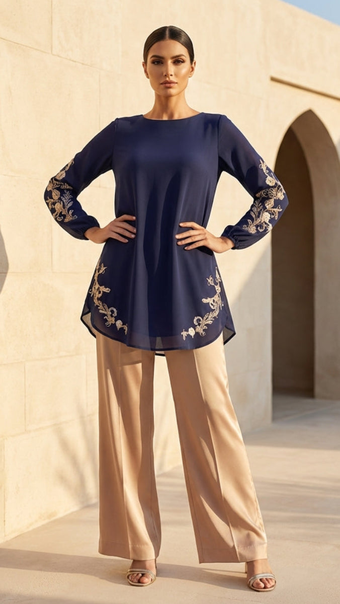 Woman wearing a navy blue top with floral embroidery and beige pants standing in front of a beige building.