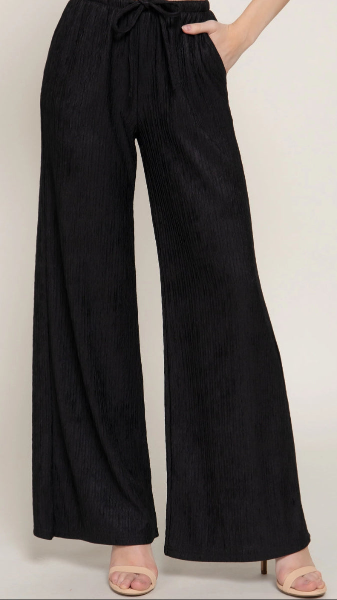 Black wide-leg pants worn by a person on a plain background