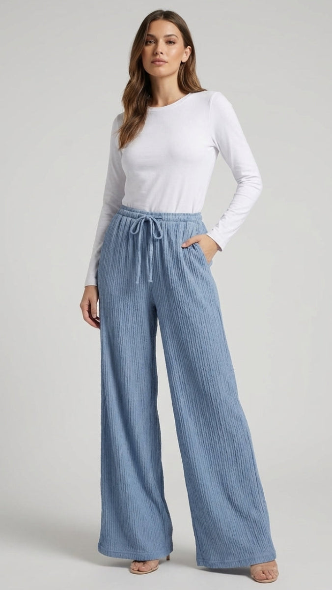 Woman wearing a white top and blue striped pants on a gray background