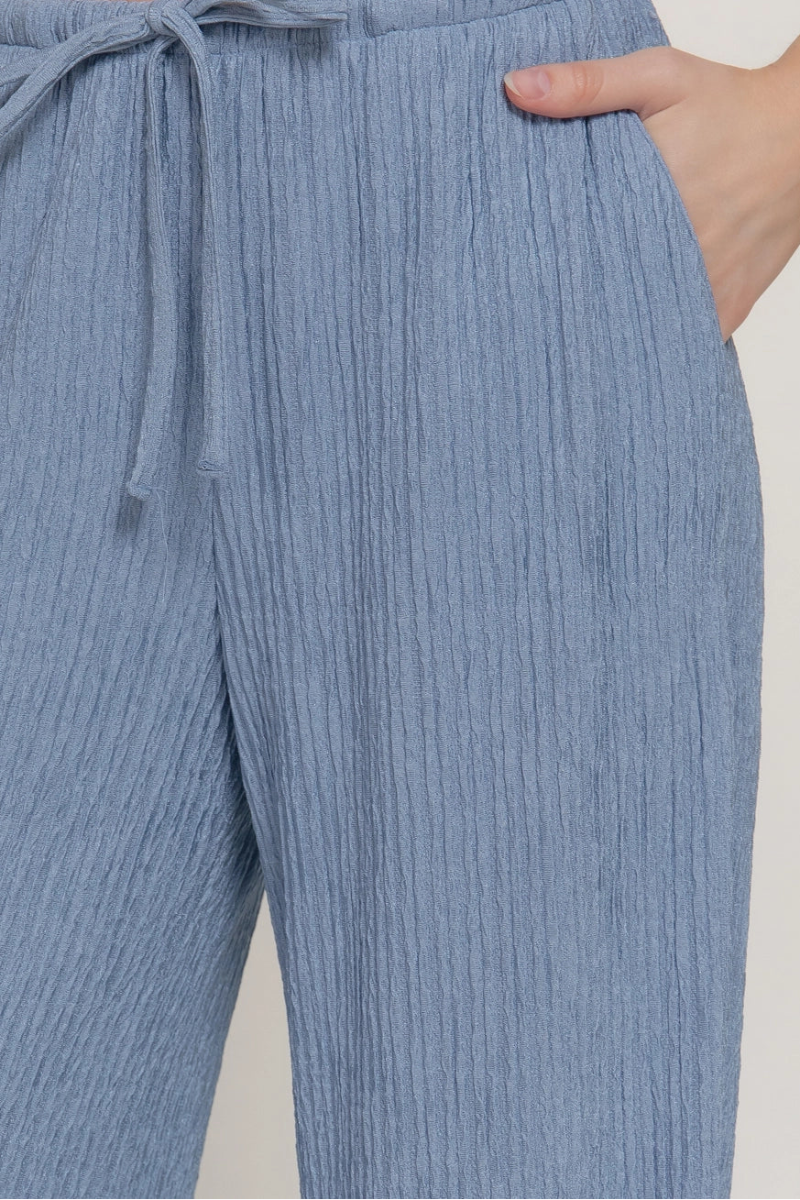 Blue ribbed pants with a drawstring waist on a plain background