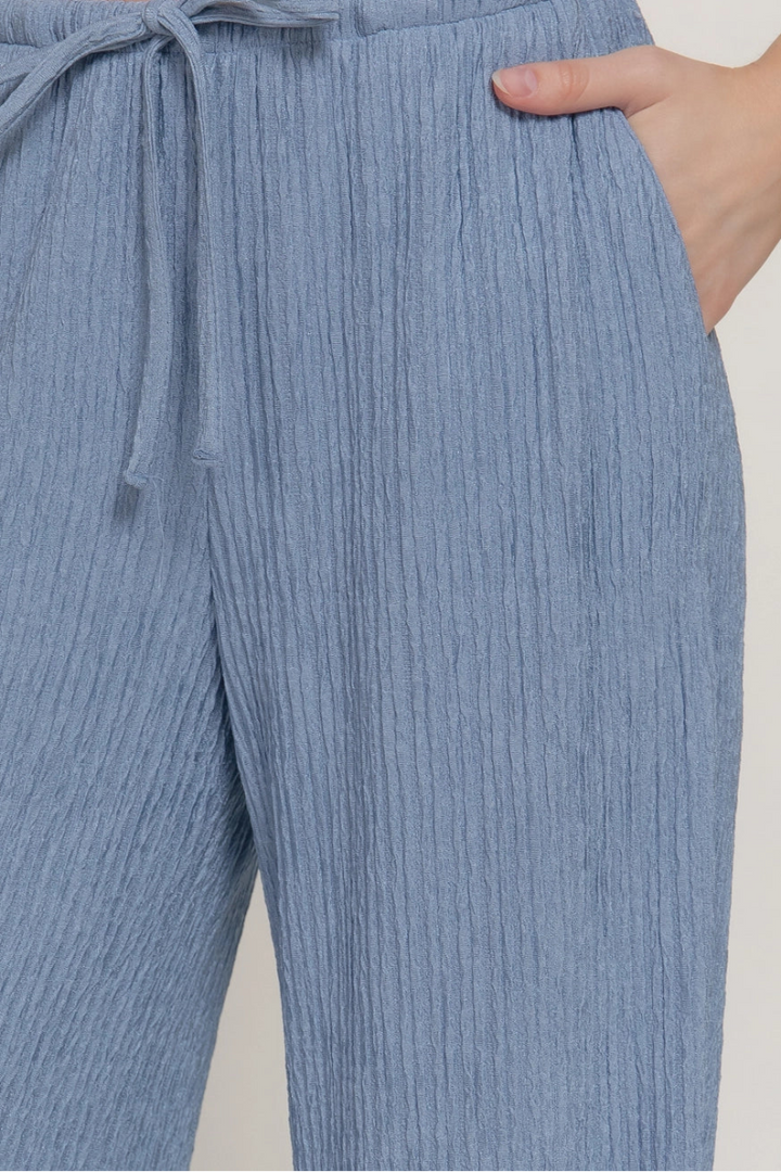 Blue ribbed pants with a drawstring waist on a plain background