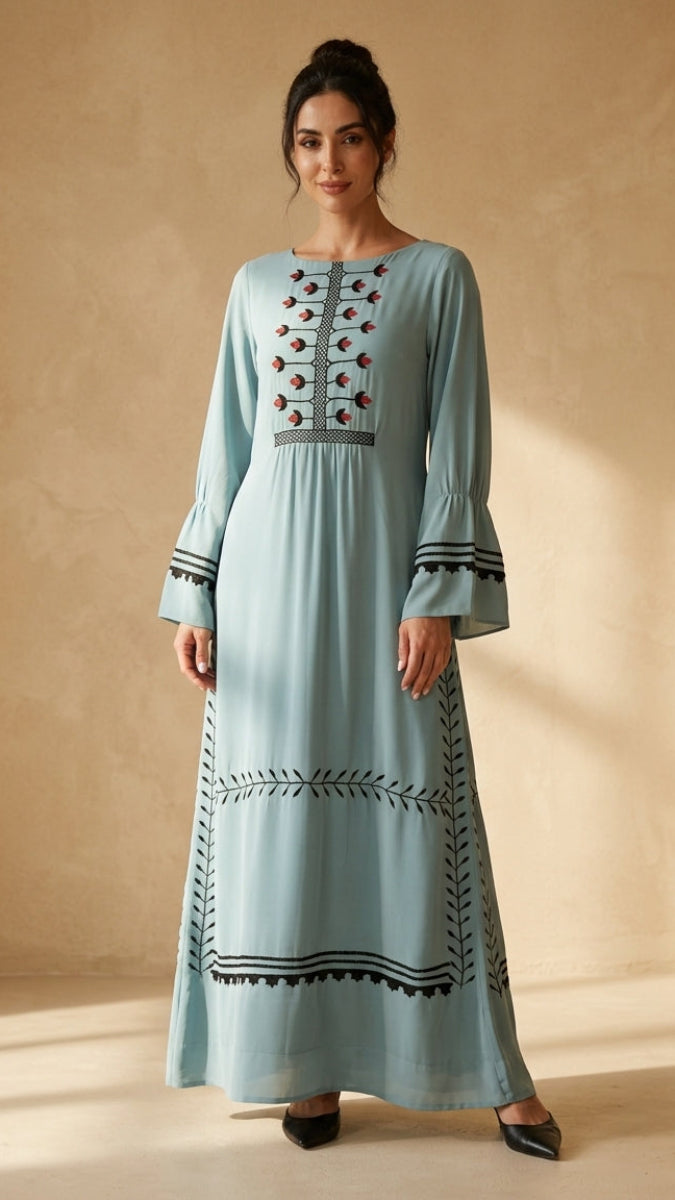 Woman wearing a light blue dress with intricate patterns on a beige background