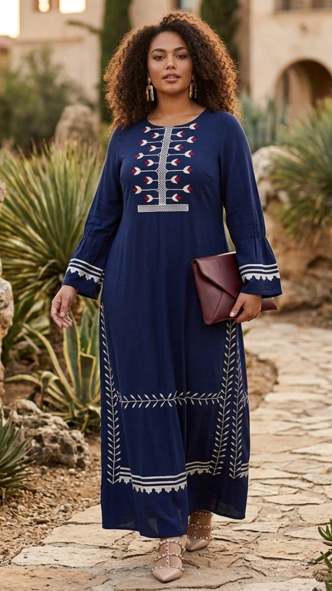 Woman in a blue dress with white patterns standing in a garden setting.
