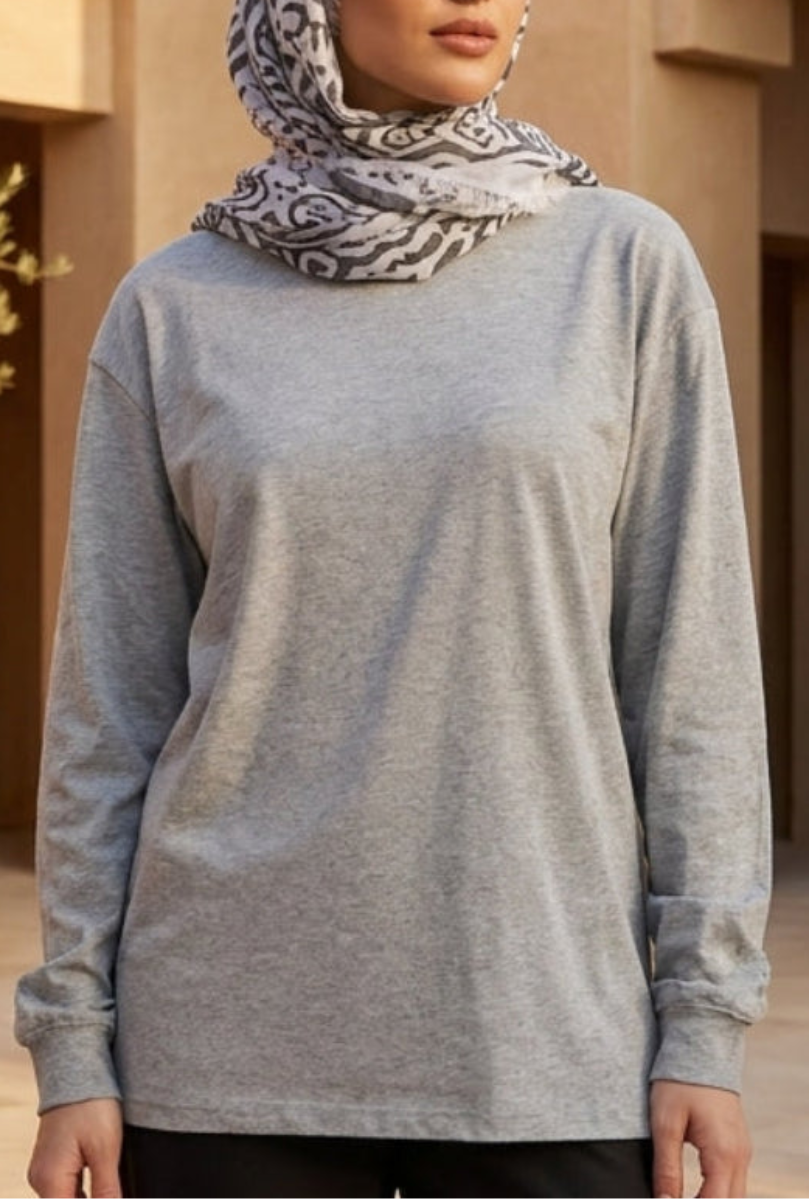 Person wearing a gray long-sleeve top with a patterned headscarf in an outdoor setting.