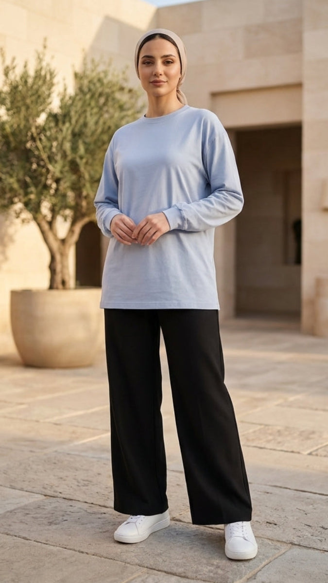 Woman standing in a courtyard with architectural elements and plants.