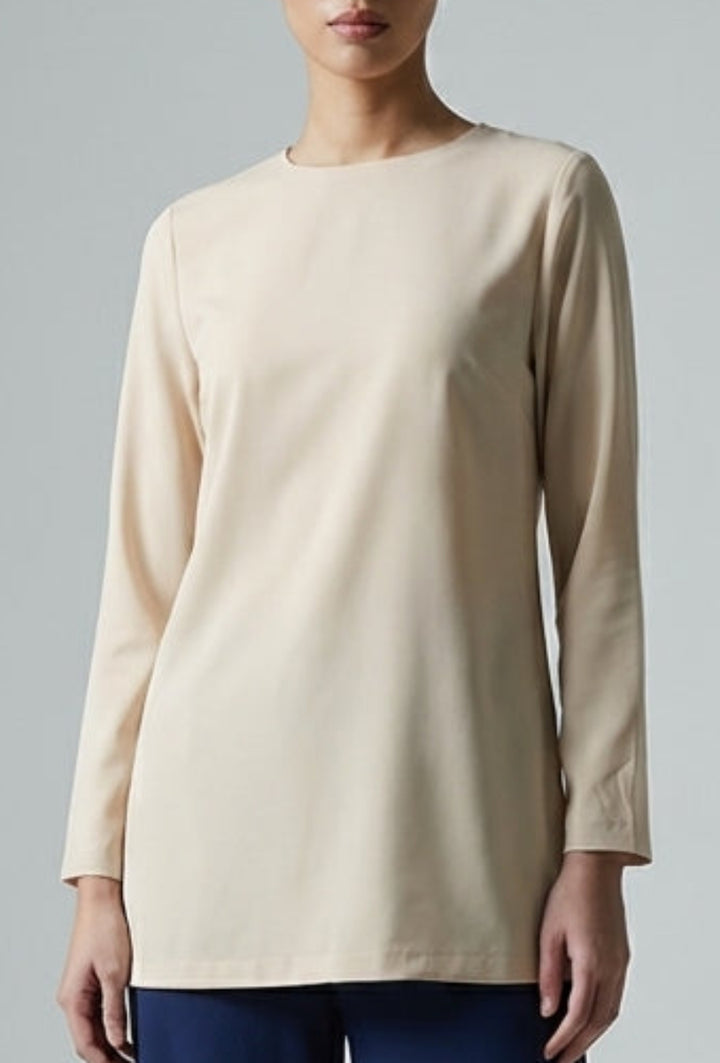 Woman wearing a beige top and navy pants on a gray background