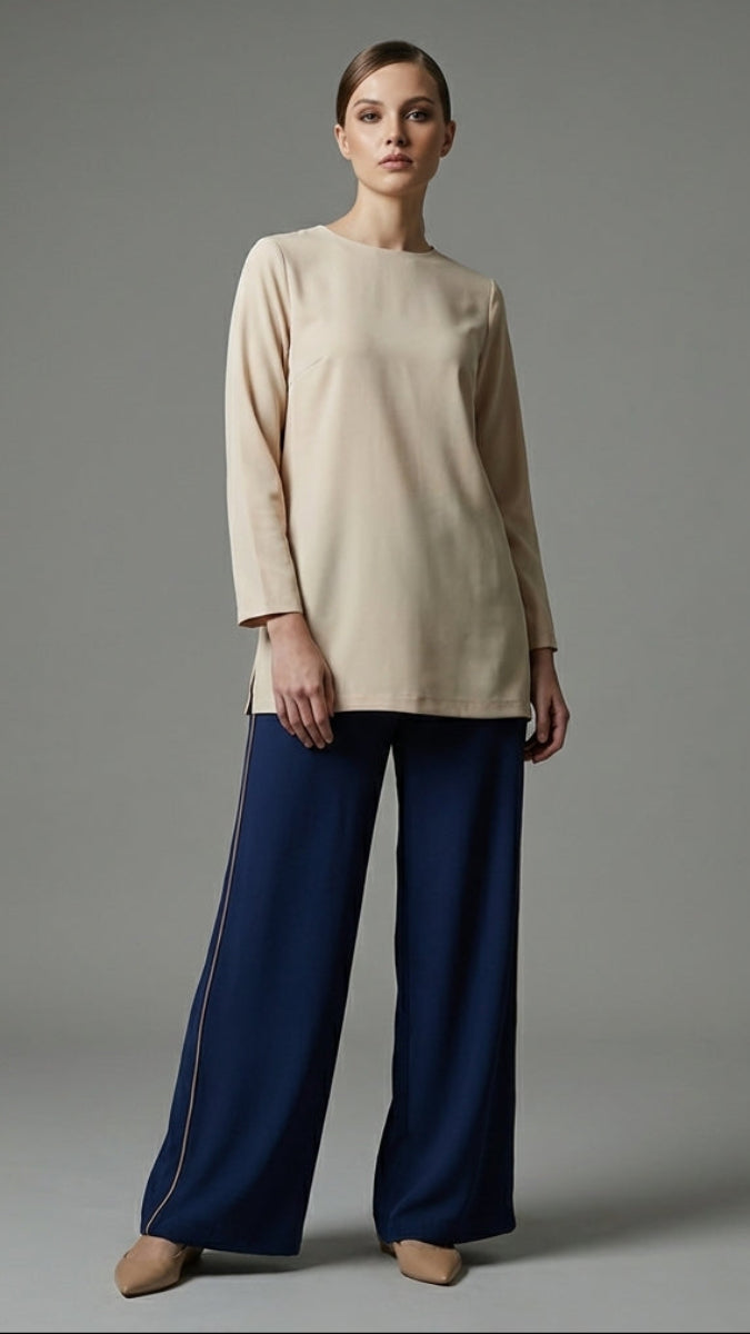 Woman wearing a beige top and blue pants on a gray background