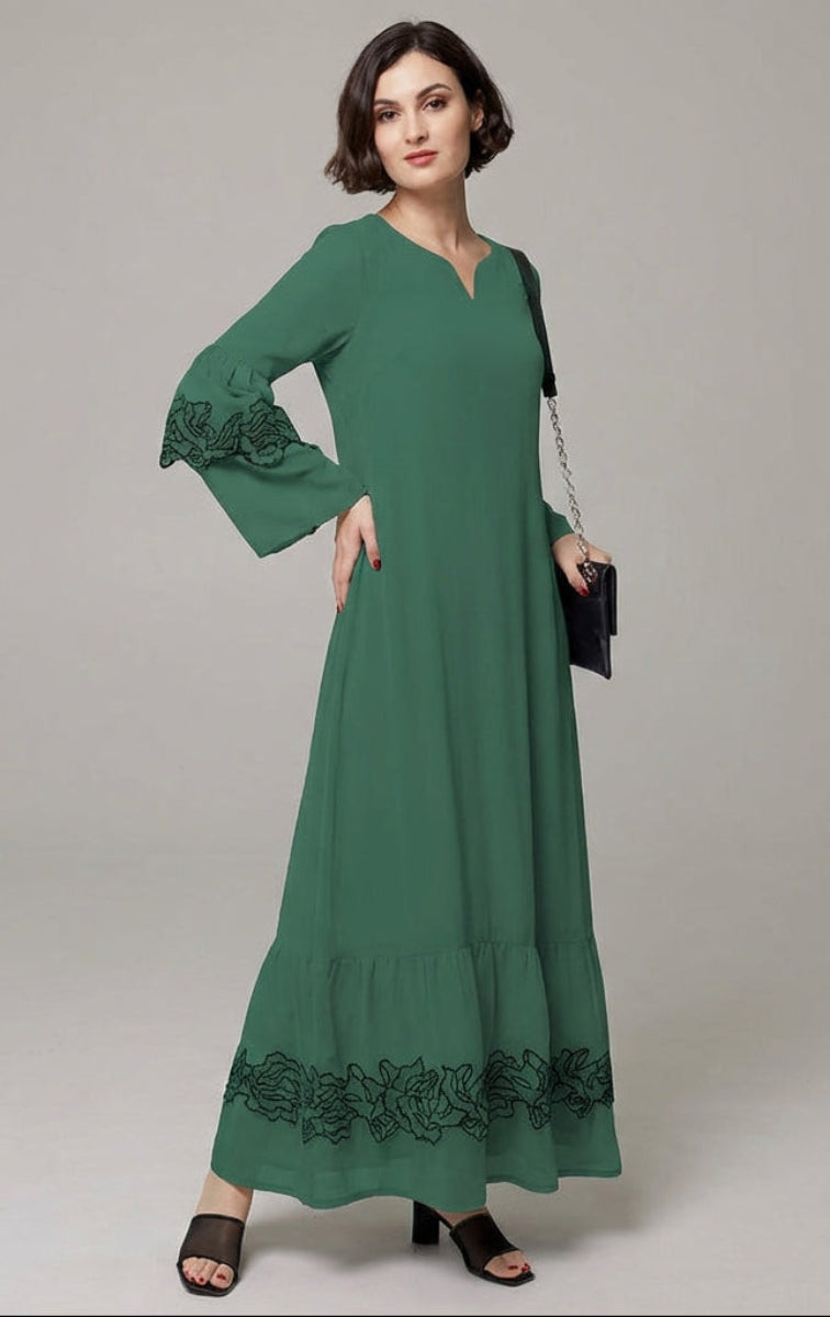 Woman wearing a green dress with floral embroidery on a gray background