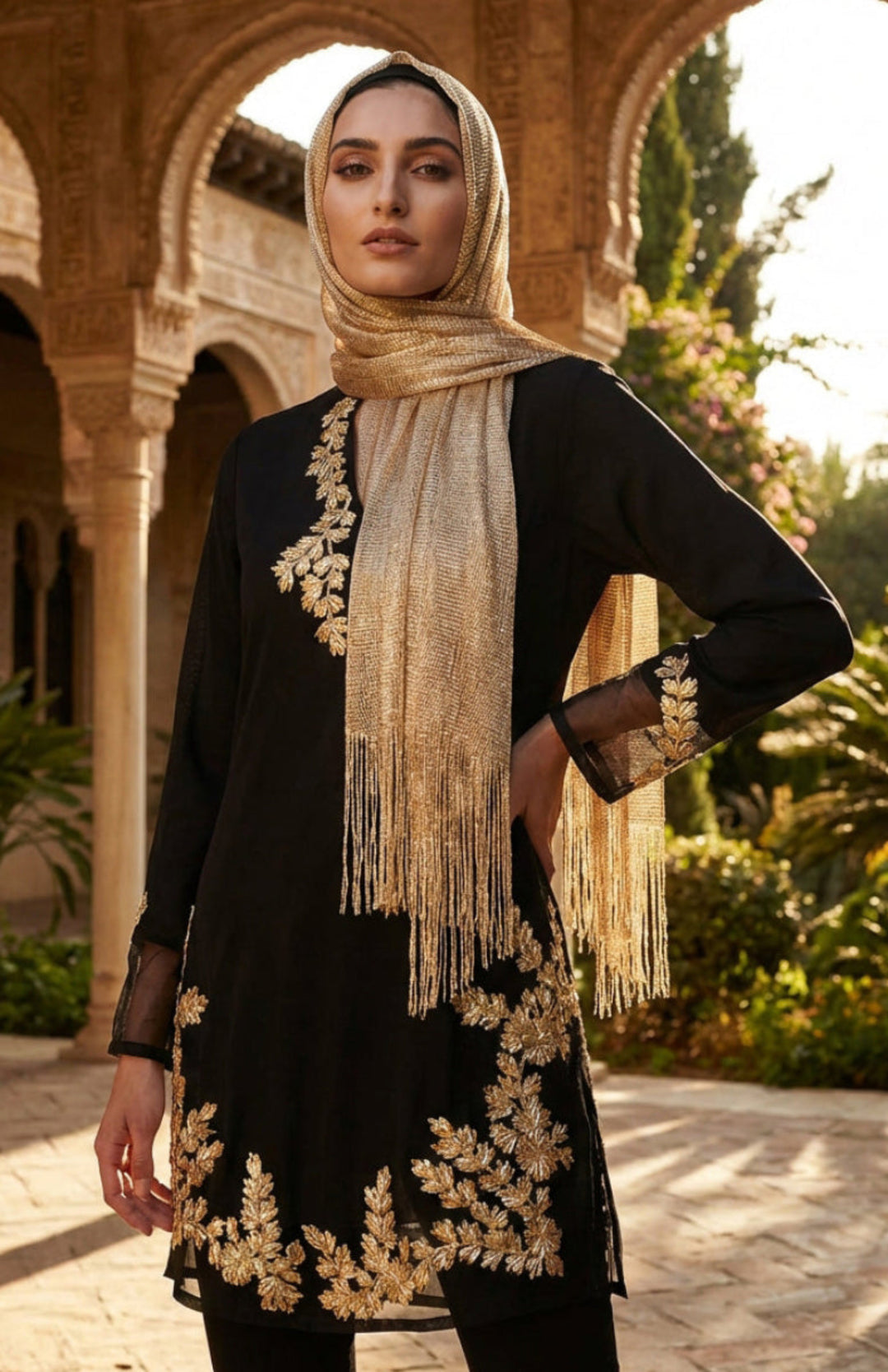 Woman wearing a black outfit with gold embroidery and a matching headscarf in an outdoor setting.