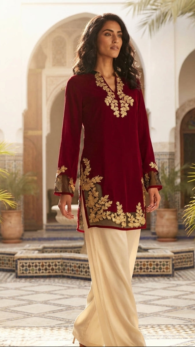 Woman in a red and gold embroidered outfit standing in an ornate courtyard.