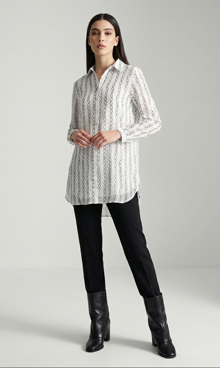 Woman wearing a white patterned shirt and black pants on a gray background