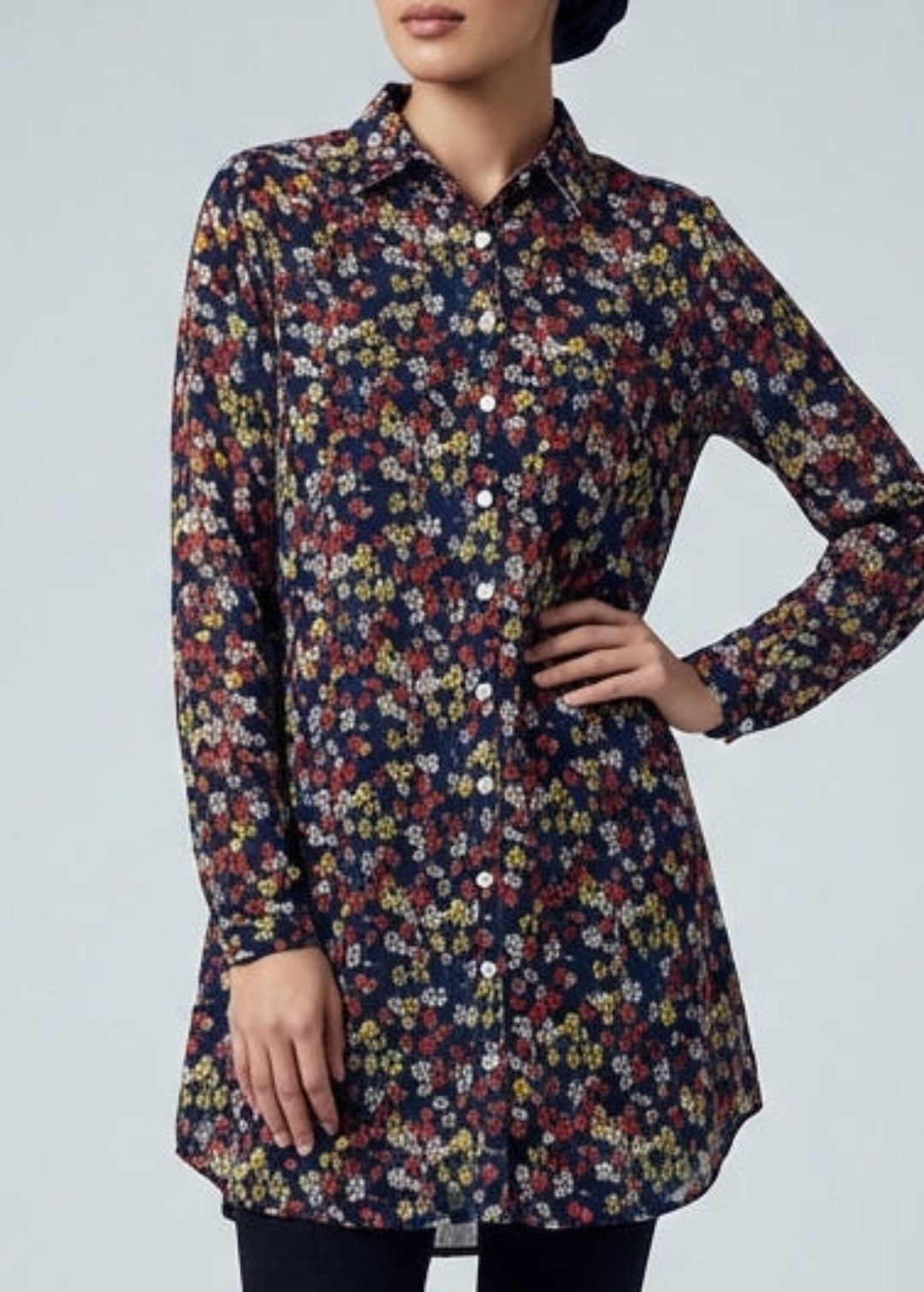 Woman wearing a patterned shirt and black hijab on a gray background