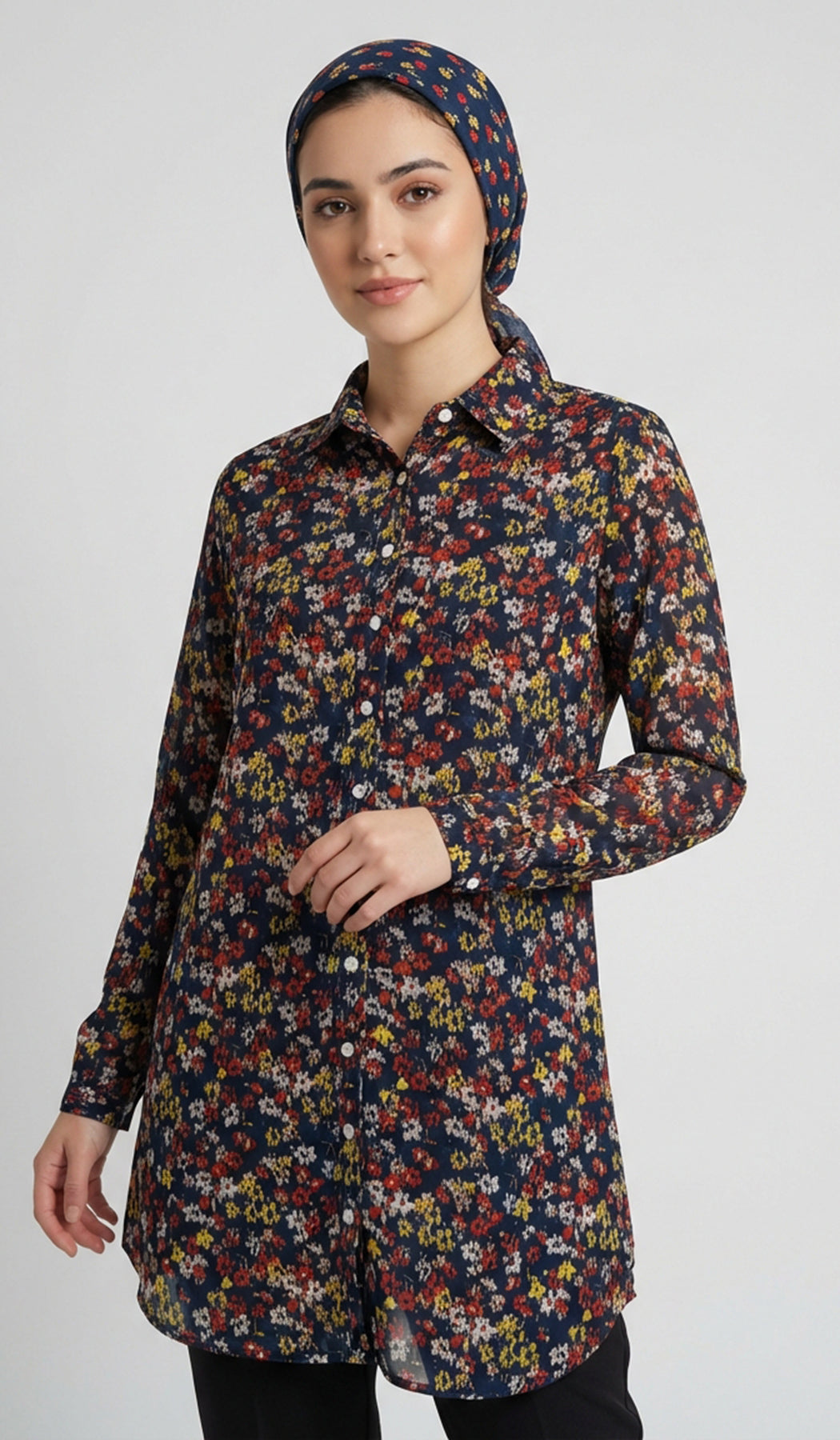Woman wearing a long, floral-patterned shirt with a plain background