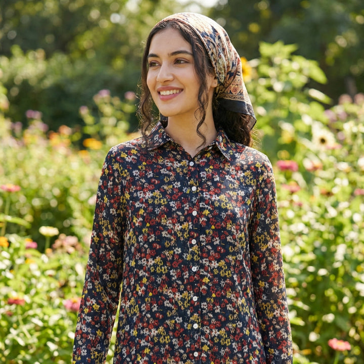 Woman wearing a floral dress and headscarf standing in a garden
