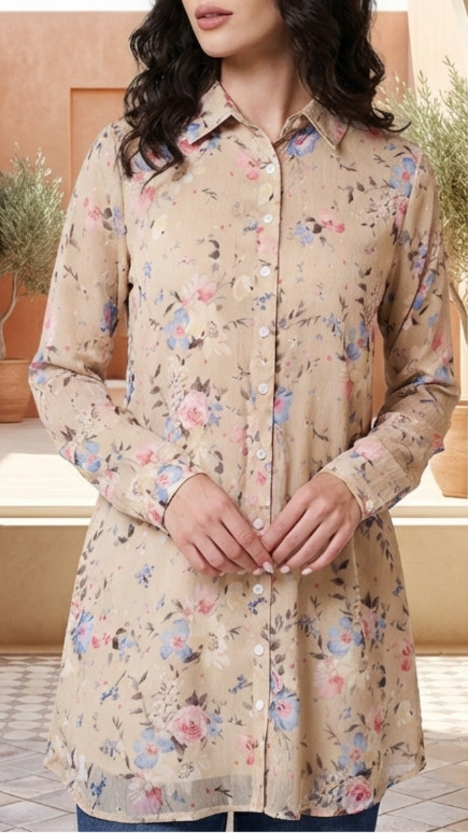Woman wearing a floral beige shirt standing in a sunlit room with archway and decorative vases.