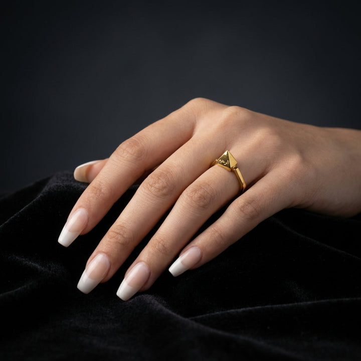 Hand wearing a gold ring on a black background