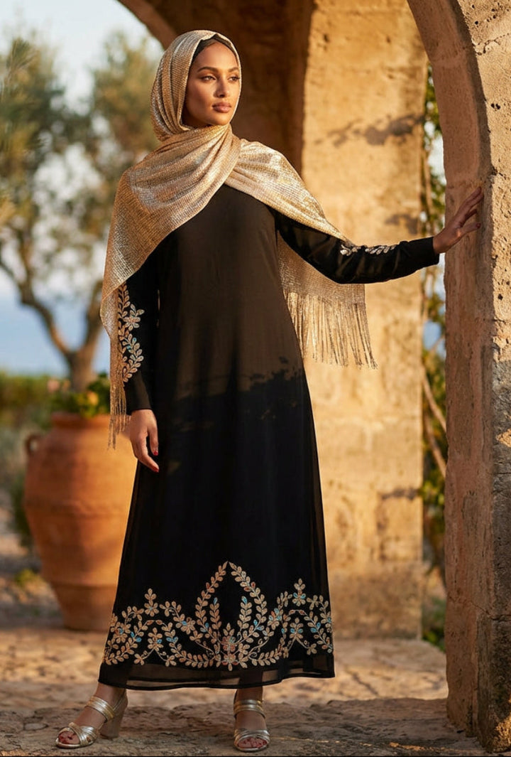 Woman in a black dress with embroidery standing in a rustic outdoor setting.