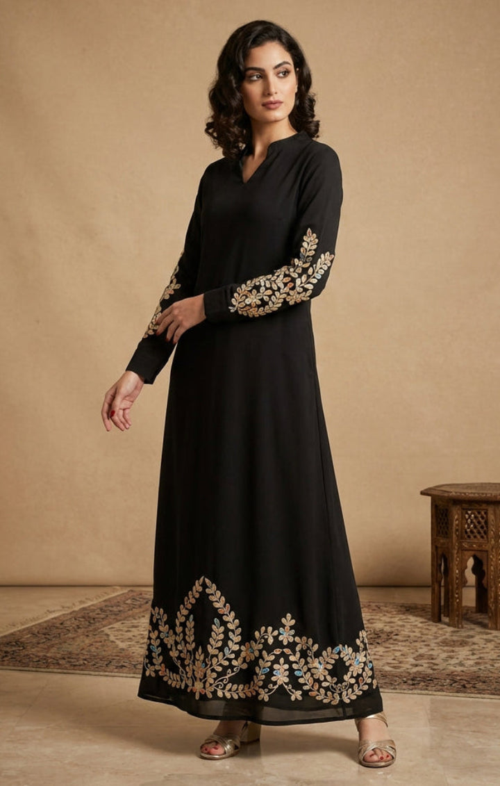 Woman wearing a black dress with gold embroidery in a studio setting
