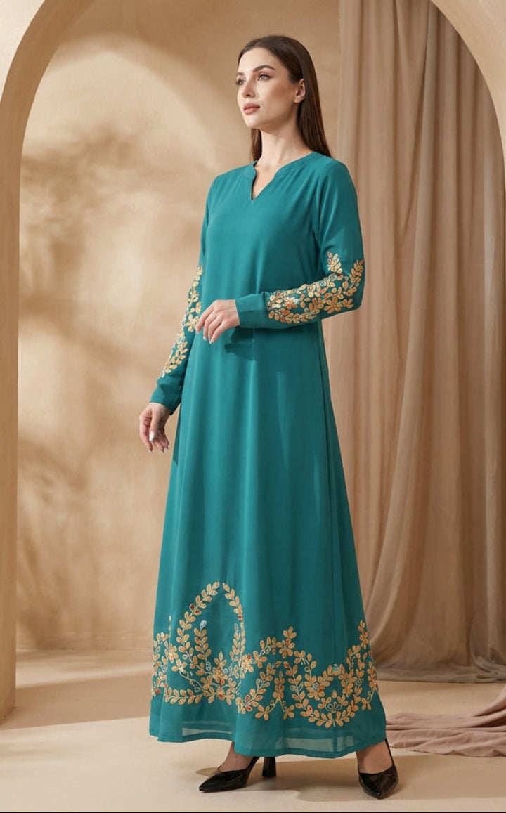 Woman wearing a teal dress with gold embroidery in a beige setting